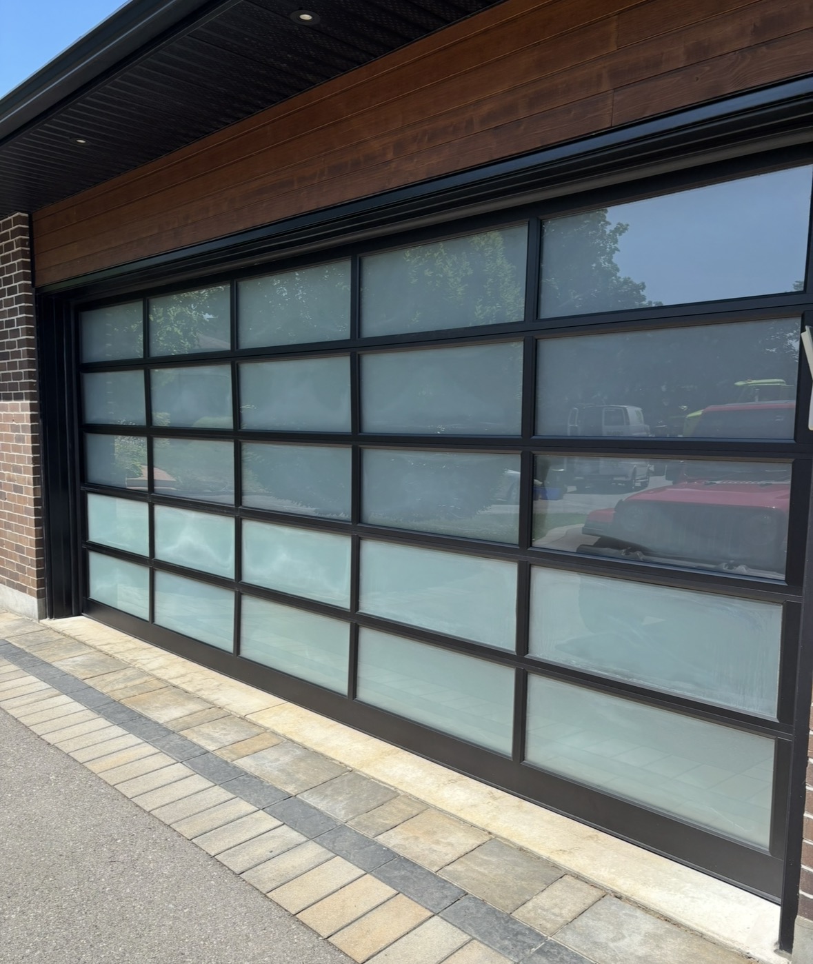 Clean glass panels of a modern garage door reflecting trees and sky