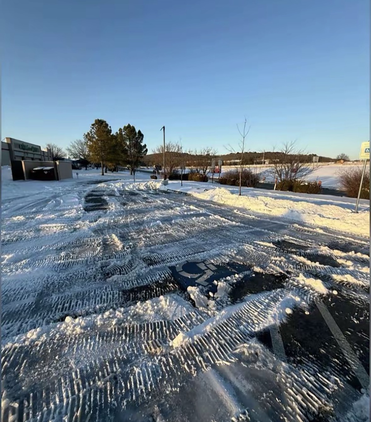 Cleared and sanded commercial parking lot with fresh tire tracks in the snow