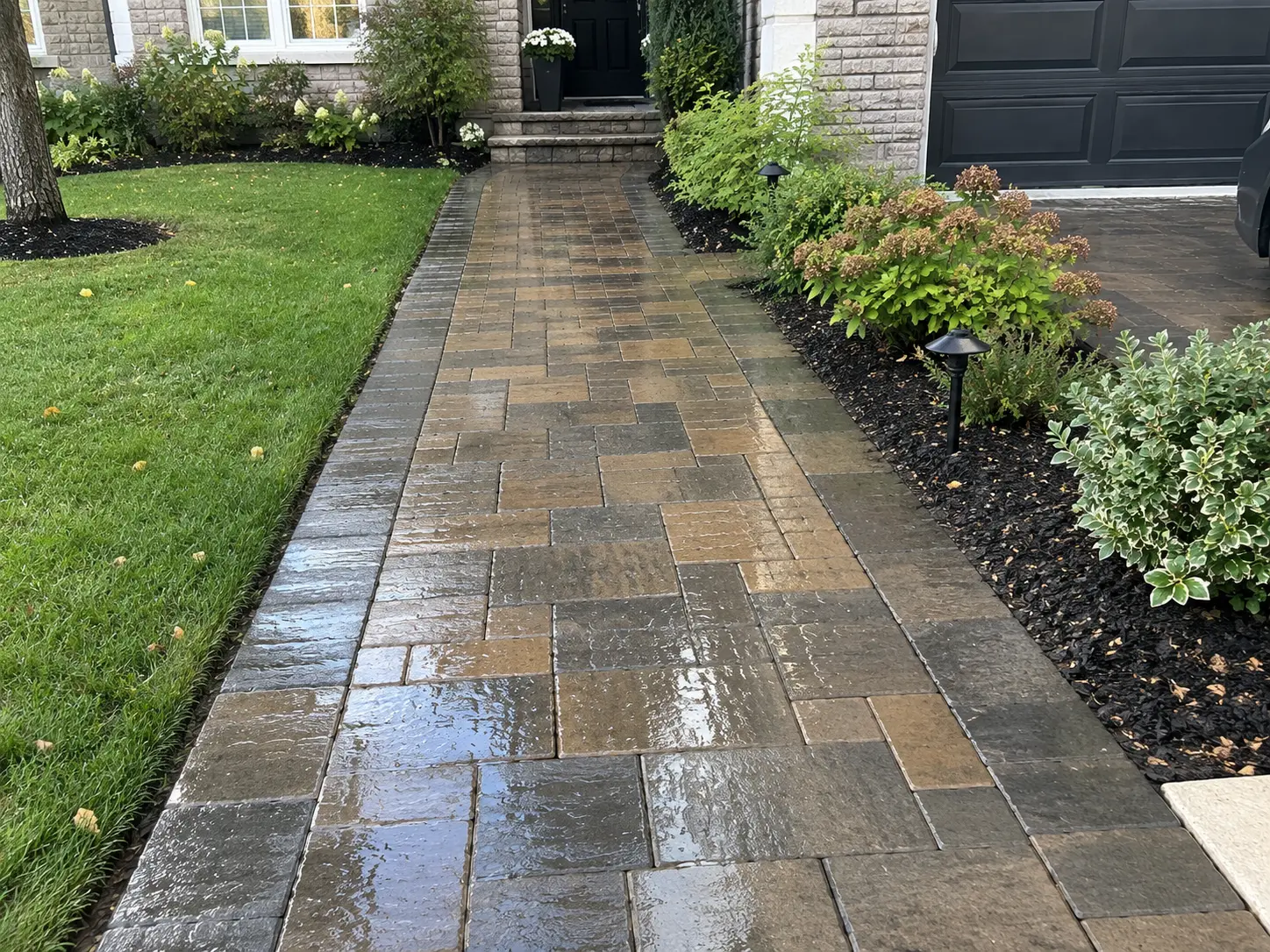 Paver walkway leading to a front door, with a wet, glossy surface